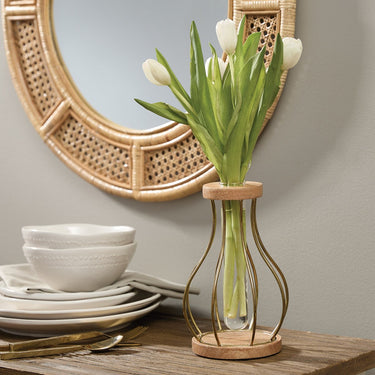 Decorative vase with tulips on a table against a wall with a round mirror.